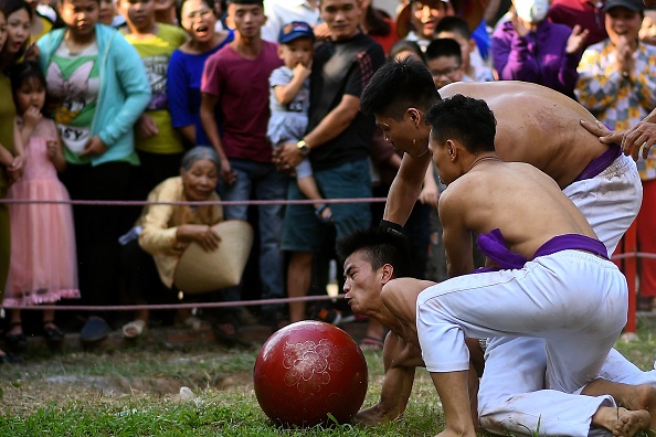 -Cette photo prise le 9 février 2019 montre des habitants regardant des hommes se disputer le ballon en bois de jaquier lors du traditionnel festival « Vat Cau », le cinquième jour des célébrations du Nouvel An lunaire, au Vietnam, sous le nom de Têt, à Hanoi. Photo de Manan VATSYAYANA / AFP / Getty Images.