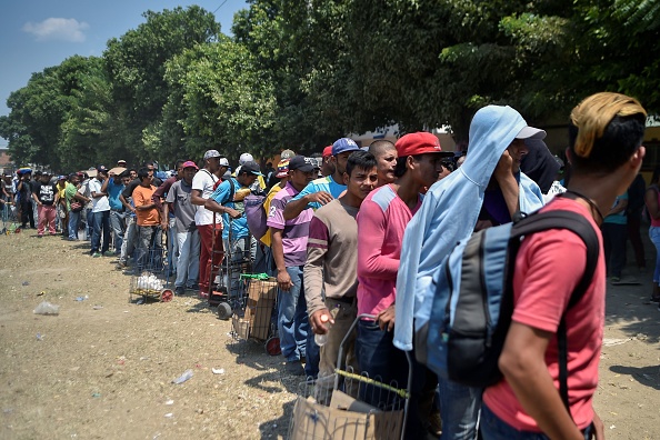 -Des migrants vénézuéliens font la queue pour recevoir de la nourriture devant le refuge de La Divina Pastora à Villa del Rosario, en Colombie, à la frontière avec le Venezuela, le 13 février 2019. La Divina Pastora, alimente quotidiennement plus de 4 000 migrants vénézuéliens. Photo de Luis ROBAYO / AFP / Getty Images.