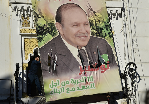 Des manifestants algériens démolissent un grand panneau d'affichage sur lequel figure une photo de leur président actuel Abdelaziz Bouteflika, lors d'une manifestation contre sa candidature pour un cinquième mandat, le 22 février 2019 à Alger.  (Photo :  RYAD KRAMDI/AFP/Getty Images)
