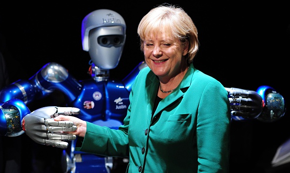 -La chancelière allemande Angela Merkel plaisante avec 'SpaceJustin', un robot humanoïde lors de l'exposition internationale de l'aérospatiale (ILA) le 8 juin 2010 à l'aéroport Schoenefeld de Berlin photo JOHANNES EISELE / AFP / Getty Images.