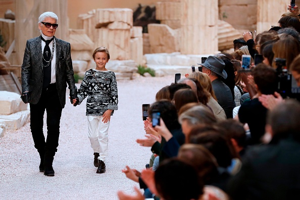 -Le couturier allemand Karl Lagerfeld rend hommage au public avec son filleul Hudson Kroenig à l'issue du défilé Chanel Croisière du 3 mai 2017 au Grand Palais à Paris. Photo de Patrick KOVARIK / AFP / Getty Images.