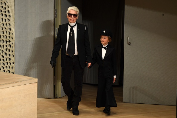 -Le couturier allemand Karl Lagerfeld et son filleul Hudson Kroenig entrent en scène après que des modèles aient présenté des créations lors du défilé de Chanel au salon Elbphilarmonie à Hambourg, dans le nord de l'Allemagne, le 6 décembre 2017. Photo PATRIK STOLLARZ / AFP / Getty Images.