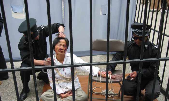 Une reconstitution de la torture d'une pratiquante de Falun Gong par des policiers dans un centre de détention. (Minghui.org)
