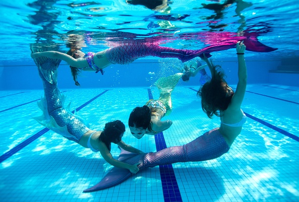 -Les étudiantes, de l’académie de danse de sirènes sont vêtues de haut de maillot de bain et de queues de sirènes, nagent en rond sous l'eau. Photo de Mohd RASFAN / AFP / Getty Images.