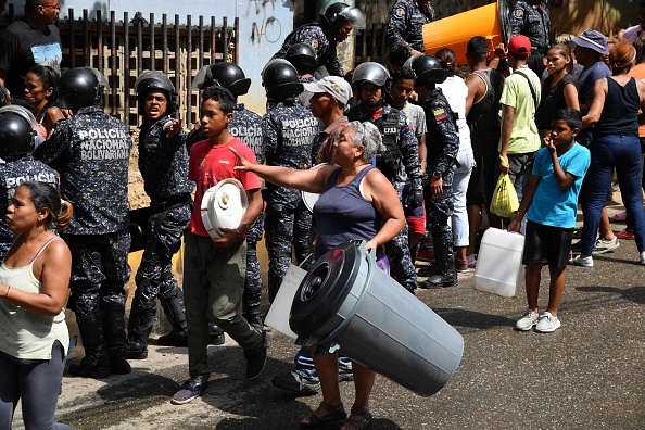 -Des membres de la police nationale bolivarienne aident à organiser la distribution d'eau potable aux habitants du quartier de San Agustín à Caracas le 11 mars 2019, alors qu'une panne de courant massive continue de toucher certaines parties du pays. Photo de Yuri CORTEZ / AFP / Getty Images.