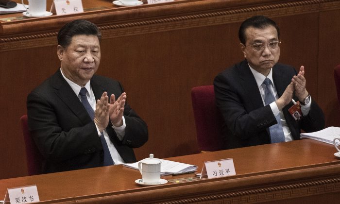 Le dirigeant chinois Xi Jinping (à g.) et le Premier ministre Li Keqiang applaudissent lors de la troisième séance plénière de l'Assemblée populaire nationale, au Grand palais du Peuple à Pékin, le 12 mars 2019. (Kevin Frayer/Getty Images)