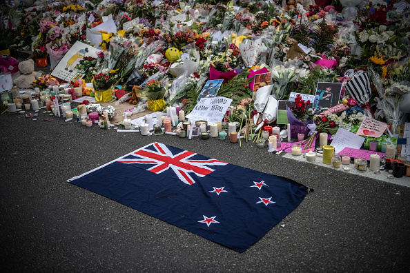 -Un drapeau de la Nouvelle-Zélande est placé à côté de fleurs et des hommages près de la mosquée Al Noor le 18 mars 2019 à Christchurch, en Nouvelle-Zélande. Photo de Carl Court / Getty Images.