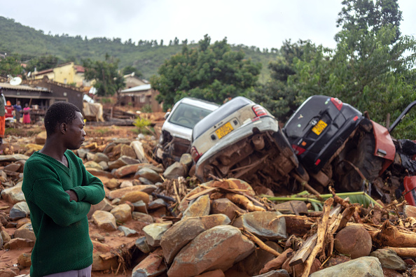 Un homme se tient à côté des épaves de véhicules le 18 mars 2019 à Chimanimani, dans l'est du Zimbabwe, après le passage du cyclone Idai dans la région. Un cyclone qui a dévasté le Mozambique et le Zimbabwe a fait les nombreux morts disparus. Le cyclone Idai s'est abattu sur le centre du Mozambique dans la nuit du 14 mars, avant de se diriger vers le Zimbabwe voisin, provoquant des inondations soudaines et des vents violents. (Photo : ZINYANGE AUNTONY/AFP/Getty Images)