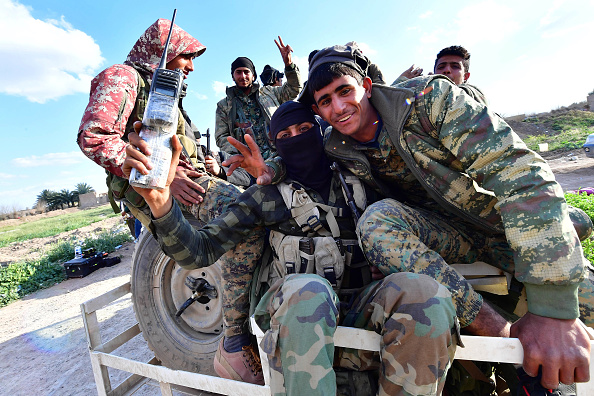 -Des combattants des Forces démocratiques syriennes (SDF) font le signe de « V » pour la victoire emportée. C’est le retour du front dans la dernière position du groupe État islamique dans le village de Baghouz dans l'est du pays. Le 19/03/ 2019. Photo par GIUSEPPE CACACE / AFP / Getty Images.