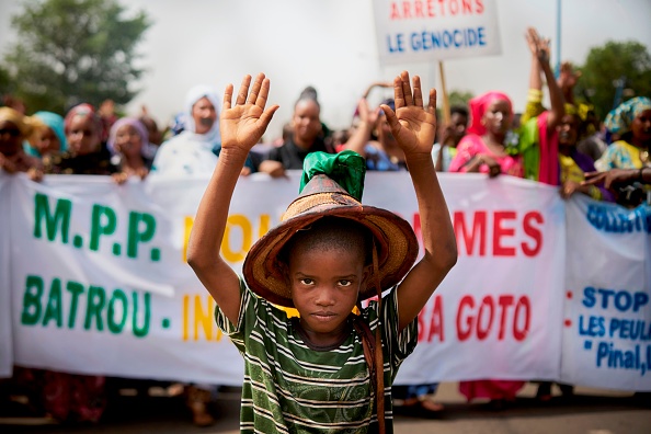 -Un jeune Peul proteste devant une pancarte « Halte au génocide » lors d'une marche silencieuse organisée par le Mouvement Peul et ses alliés pour la paix à Bamako en réponse à un massacre à Koumaga, au Mali. A la suite d'une attaque dans le centre du Mali, qui aurait été perpétrée par des chasseurs musulmans. Photo de MICHELE CATTANI / AFP / Getty Images.