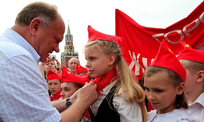 Gennady Ziouganov, chef du Parti communiste russe, attache des foulards rouges autour du cou des enfants, symbolisant leur initiation au groupe communiste des Jeunes pionniers créé en Union soviétique pour les enfants de 10-14 ans, dans la place Rouge à Moscou. (Alexey SAZONOV/AFP/Getty Images)
