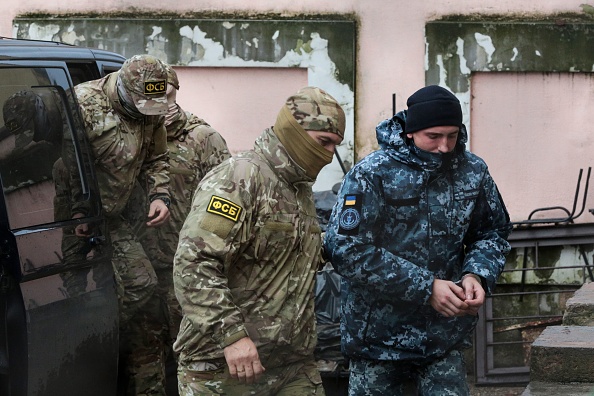 -Un officier des services de sécurité russes du FSB escorte un marin ukrainien détenu jusqu'à un palais de justice en Crimée, le 27 novembre 2018. Plusieurs autres des plus de 20 marins ukrainiens détenus par la Russie devraient aussi comparaître devant ce même tribunal. Photo de STR / AFP / Getty Images.