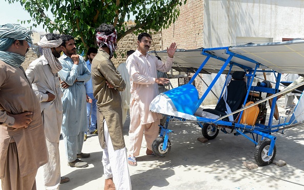 -Sur cette photo prise le 8 avril 2019, le villageois pakistanais Muhammad Fayyaz parle aux visiteurs alors qu'il se tient à côté de son petit avion dans sa résidence du village de Tabur dans la province centrale du Punjab. Le moteur provient d'un bûcheron, les ailes sont en toile de jute, les roues sont empruntées à un pousse-pousse : un vendeur de pop-corn pakistanais a attiré l'attention de l'armée de l'air en construisant son propre avion. Photo par ARIF ALI / AFP / Getty Images.