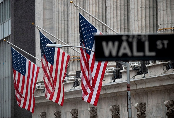 -La plaque de rue «Wall St» est vue près des drapeaux américains devant la Bourse de New York (NYSE) le 23 mai 2019. Photo de Johannes EISELE / AFP / Getty Images.
