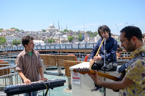 -Les musiciens Oguzhan Erdem jouent le ney, le clavier d'Eren Koc et la guitare de Zafer Saka lors d'un voyage en ferry sur le Bosphore de Kadikoy à Eminonu, à Istanbul, le 16 mai 2019. Et maintenant, l'expérience est devenue encore plus charmante, la ville offrant gratuitement de la musique de musiciens amateurs pour accompagner les magnifiques paysages marins. Photo de BULENT KILIC / AFP / Getty Images.