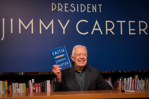 -L'ancien président américain Jimmy Carter brandit un exemplaire de son nouveau livre « La foi un voyage pour tous » lors d'une séance de dédicaces à la librairie Barnes & Noble à Midtown Manhattan, le 26 mars 2018 à New York Ville. Carter, âgé de 93 ans, est un auteur prolifique depuis qu'il a quitté ses fonctions en 1981. Photo de Drew Angerer / Getty Images.
