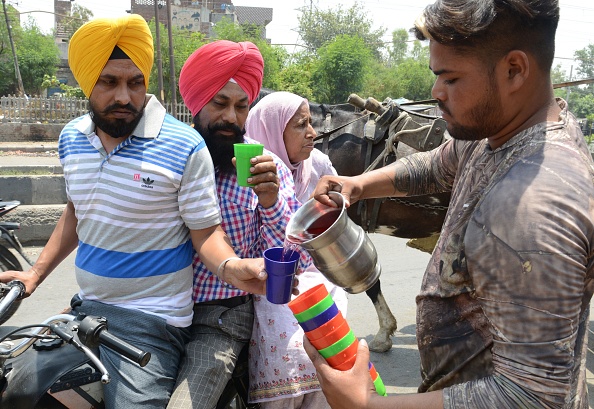 Un volontaire indien distribue de l'eau douce pendant une chaude journée d'été à Amritsar, le 2 juin 2019. Les températures dépassent les 50 degrés Celsius dans le nord de l'Inde. Une vague de chaleur incessante a déclenché des avertissements de pénurie d'eau et de coup de chaleur. Photo de Narinder NANU / AFP / Getty Images.