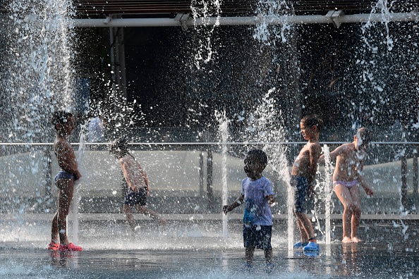 Des enfants s'amusent avec des sources d'eau sur la place Aulenti à Milan pendant la canicule du 26 juin 2019. (Photo :  Miguel MEDINA / AFP / Getty Images)