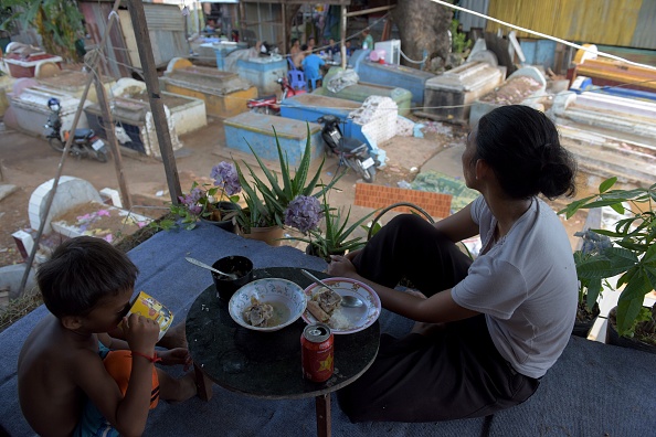 -Une femme cambodgienne déguste son repas chez elle au-dessus des tombes dans un village de bidonvilles de Phnom Penh le 11 avril 2017. Photo TANG CHHIN SOTHY / AFP / Getty Images.