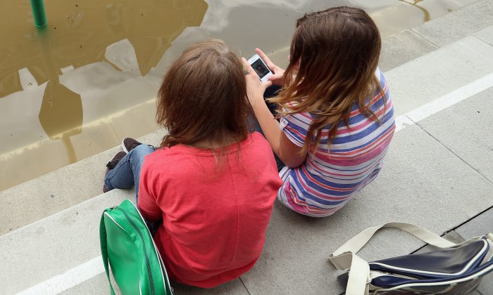Deux fillettes sont assises et discutent d'applications qu'elles ont sur leur téléphone. (Sean Gallup/Getty Images)
