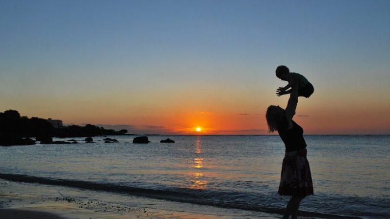 Illustration d'une mère soulevant son fils à la plage. (Pixabay)