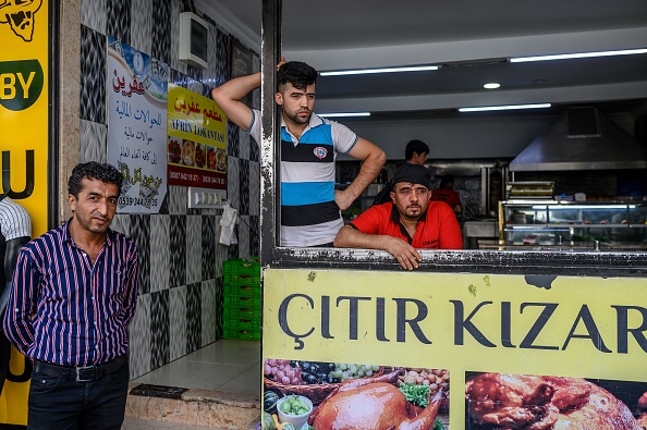 -Des employés qui travaillent pour un restaurant syrien nommé Afrin se tiennent devant le restaurant endommagé dans le quartier populaire de Kucukcekmece à Istanbul le 5 juillet 2019. La Turquie abrite le plus grand nombre de réfugiés au monde, ayant accueilli plus de 3,5 millions de Syriens dont 500 000 à Istanbul. Photo de BULENT KILIC / AFP / Getty Images.
