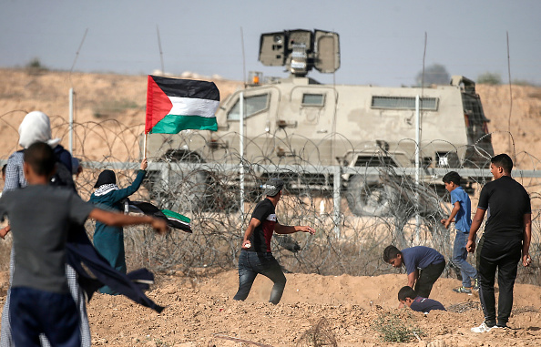 -Des manifestants palestiniens lancent des pierres sur les forces de sécurité israéliennes lors de manifestations le 12 juillet 2019, dans le sud de la bande de Gaza. Photo de MAHMUD HAMS / AFP / Getty Images.