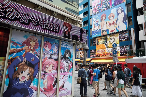 -Des gens défilent devant des images de personnages de mangas et d'animés dans le quartier d'Akihabara à Tokyo le 19 juillet 2019. L'incendie apparemment d’origine criminelle a été perpétré le 12 juillet à Kyoto dans une société d’animation japonaise réputée, Kyoto Animation. Photo par Behrouz MEHRI / AFP / Getty Images.