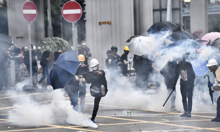 La police anti-émeute a tiré des gaz lacrymogènes sur des manifestants lors d'une manifestation dans le district de Yuen Long à Hong Kong le 27 juillet 2019. - Des policiers émeutiers ont tiré des gaz lacrymogènes sur des manifestants défilant dans une ville de Hong Kong près de la frontière chinoise pour se rassembler contre une présumée triade des gangs qui ont passé à tabac des manifestants favorables à la démocratie le week-end dernier (Anthony WallaceE / AFP / Getty Images)