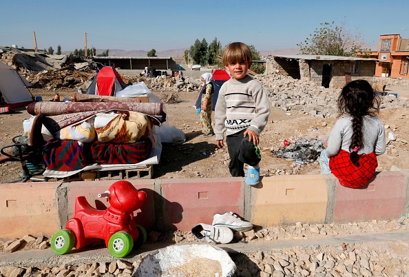 -Une photo prise lors du précédent séisme le 15 novembre 2017 montre des enfants iraniens à côté des ruines de leur maison dans le village de Kouik. L’Iran est une zone de forte activité sismique. Photo ATTA KENARE / AFP / Getty Images.
