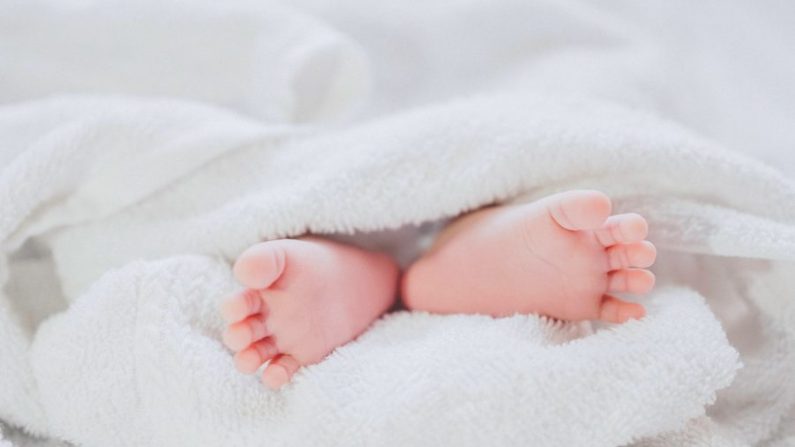 Illustration d'un bébé enveloppé dans des couvertures, les pieds pointés vers l'extérieur. (Fé Ngô / Unsplash)
