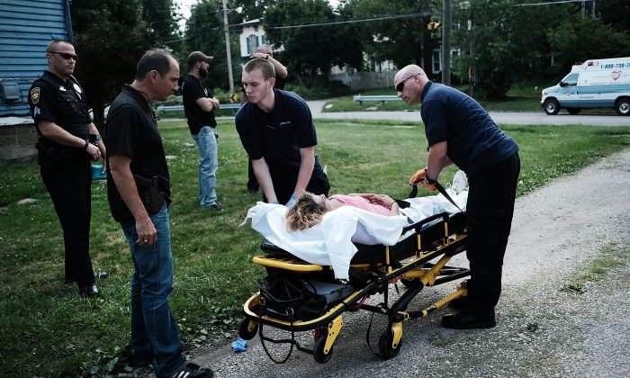 Des travailleurs médicaux et des policiers donnent les premiers soins à une femme faisant une surdose d'héroïne, à Warren, dans l'Ohio, le 14 juillet 2017. (Spencer Platt/Getty Images)
