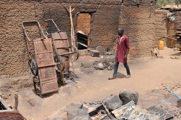 -Un homme passe devant une maison incendiée à Zeleved, dans le nord du Cameroun, le 23 mars 2019. Les habitants du village de Zeleved, situés à une zone isolée dans les montagnes, ont à peine eu une pause. Photo par Reinnier KAZE / AFP / Getty Images.