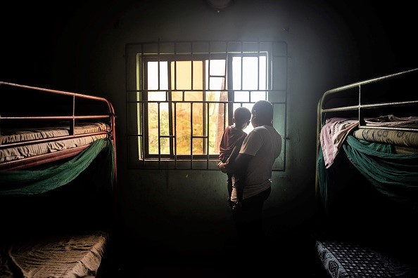 -Une femme et son enfant regardent par la fenêtre le 26 juin 2019 à Benin City, alors qu'ils se trouvaient dans l'un des abris de la Société pour l'autonomisation des jeunes (SEYP), une organisation qui réhabilite et réintègre les femmes rentrant de Libye avec des enfants en bas âge souvent né à la suite d'un viol. Photo par FATI ABUBAKAR / AFP / Getty Images.
