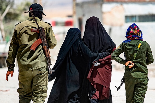 Une patrouille de sécurité intérieure escorte des épouses de combattants du groupe de l'État islamique (EI), dans le camp d'al-Hol dans le gouvernorat d'al-Hasakeh, au nord-est de la Syrie, le 23 juillet 2019. (Photo credit should read DELIL SOULEIMAN/AFP/Getty Images)