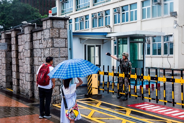 -Un soldat de l'Armée de libération du peuple chinois aide les passants à l'entrée du bâtiment des Forces de l'APL de Hong Kong. Le 1er août 2019. L'armée chinoise a publié une vidéo de propagande ludique montrant un exercice de troupes armées réprimant une manifestation à Hong Kong, un avertissement à peine voilé adressé au mouvement pro-démocratique de la ville. Des milliers de soldats de l'ALP sont basés à la garnison de Hong Kong depuis le transfert des responsabilités. Photo ISAAC LAWRENCE / AFP / Getty Images.