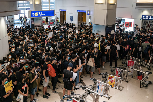 Des manifestants tiennent des pancartes lorsqu'ils bloquent la porte de départ du terminal 2 de l'aéroport international de Hong Kong lors d'une manifestation le 13 août 2019. (Photo : Anthony Kwan/Getty Images)