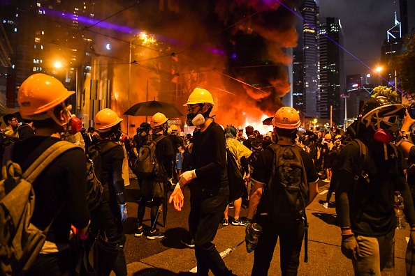 -Les manifestants se tiennent devant une barricade qu'ils ont incendiée dans le district de Wan Chai à Hong Kong le 31 août 2019. Un chaos a englouti le cœur financier de Hong Kong le 31 août alors que la police a tiré des gaz lacrymogènes et des canons à eau sur des manifestants. Photo par Lillian SUWANRUMPHA / AFP / Getty Images.