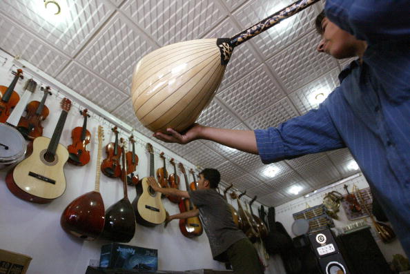 -Illustration- Un commerçant soulève un instrument à cordes kurde appelé Zambura dans un magasin de musique de la ville de Bagdad. Après la guerre les armes se transforment en musique. Photo : KARIM SAHIB / AFP / Getty Images.