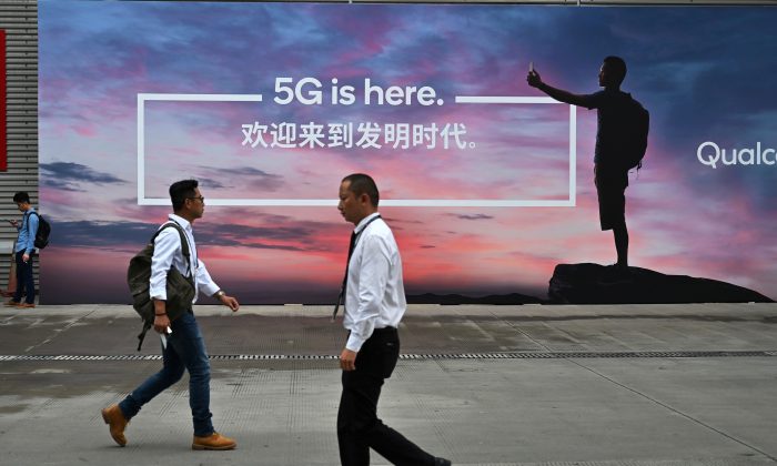 Des gens passent devant un panneau faisant la promotion de la 5G lors de Mobile World Congress (MWC 2019) qui présentait la technologie de nouvelle génération à Shanghai New International Expo Centre (SNIEC) à Shanghai, le 26 juin 2019. (Hector Retamal/AFP/Getty Images)