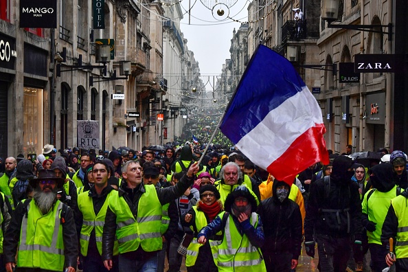 Des "gilets jaunes" manifestent dans les rues tenant un drapeau français.        (Photo : GEORGES GOBET/AFP/Getty Images)