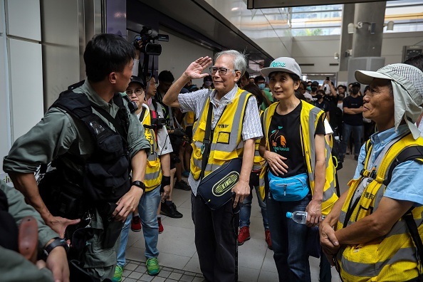 -Cette photo prise le 7 septembre 2019 montre "Grand-père Wong" 85 ans, saluant un officier de police anti-émeute ainsi que d'autres volontaires "cheveux d'argent" dans le district de Tung Chung à Hong Kong. En dépit de son âge, Wong assiste régulièrement aux batailles de rue à Hong Kong, rampant vers les lignes de police, se plaçant entre officiers anti-émeute et manifestants féroces, dans l'espoir de désamorcer ce qui est maintenant devenu des affrontements quotidiens. Photo de VIVEK PRAKASH / AFP / Getty Images.