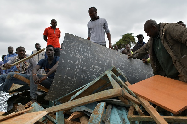 -Les résidents de la circonscription de Dagoretti à Nairobi récupèrent un tableau déchiré par les débris d'un bloc de classe effondré le 23 septembre 2019. Accident imputé à une construction de mauvaise qualité. Photo de TONY KARUMBA / AFP / Getty Images.