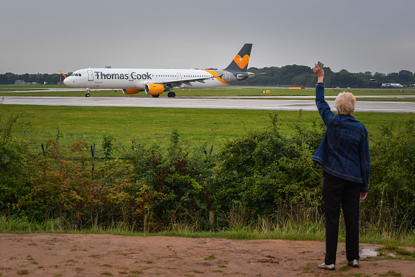 -Une femme fait signe qu'un avion de Thomas Cook quitte l'aérogare 1 de l'aéroport de Manchester le 22 septembre 2019 à Manchester, en Angleterre. Thomas Cook est déclaré lundi en faillite. Photo par Anthony Devlin / Getty Images.