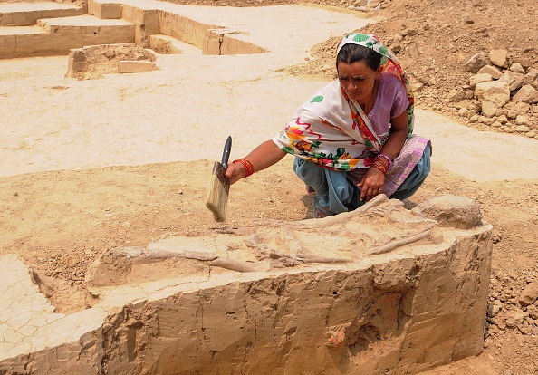 -Une femme indienne nettoie les restes d'une sépulture appartenant à la civilisation de la vallée de l'Indus lors d'une fouille archéologique sur le site de Sanauli à Baghpat le 4 juin 2018. Photo by - / AFP / Getty Images.