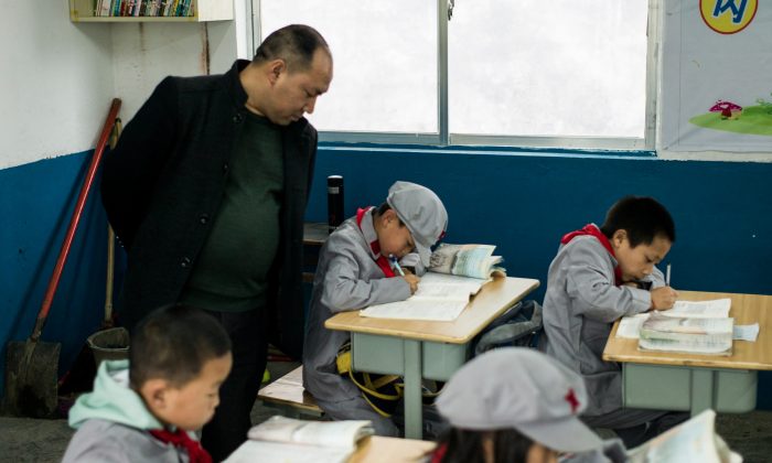 Le 7 novembre 2016, un enseignant supervise des élèves de l'école primaire de "Armée rouge" Yang Dezhi de Wenshui, dans le canton de Xishui, dans la province du Guizhou, en Chine. En 2008, Yang Dezhi a été désignée "école primaire de l'Armée rouge" - ces écoles sont un exemple extrême de "l'éducation patriotique" que le parti communiste au pouvoir en Chine promeut pour renforcer sa légitimité, mais que les critiques condamnent comme un simple lavage de cerveau. (Fred Dufour/AFP/Getty Images)