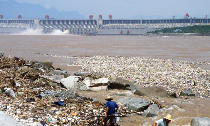 Le 1er août 2010, deux ouvriers nettoient les déchets le long de la rive du fleuve Yangtsé. Les couches de déchets flottants dans le fleuve menaçaient de bloquer l'énorme barrage hydroélectrique des Trois Gorges, situé dans la province du Hubei, au centre de la Chine, ont rapporté les médias d'État le 2 août. (China Out/STR/AFP/Getty Images)