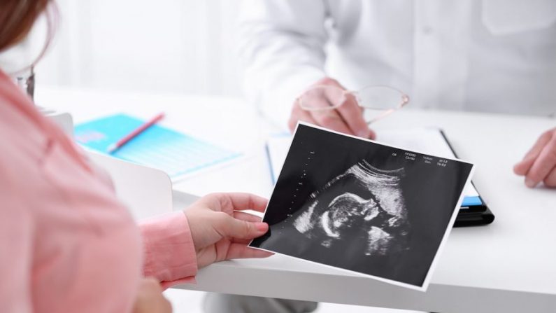 Une jeune femme enceinte lors d'une visite médicale regarde une image d'échographie. (Shutterstock)

