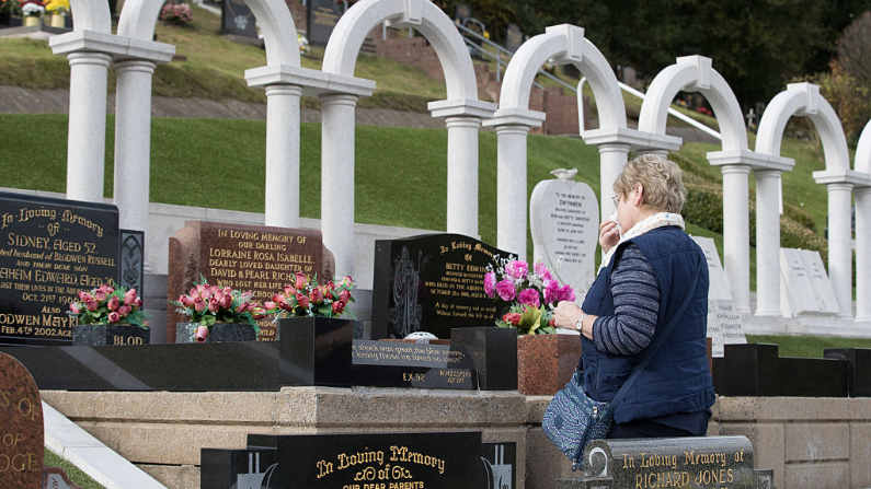 Une dame devant les tombes des victimes de la catastrophe d'Aberfan à l'occasion du 50e anniversaire de la tragédie, le 13 octobre 2016 à Aberfan, au Pays de Galles. (Matt Cardy / Getty Images)