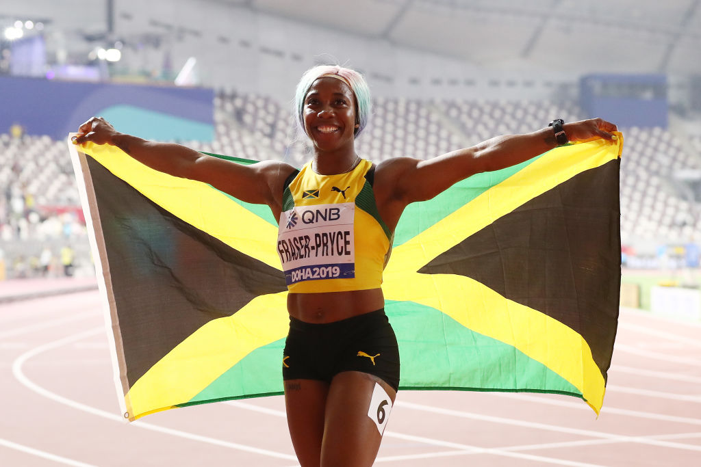 Fraser-Pryce célèbre sa victoire en hissant le drapeau jamaïcain. (©Getty Images | Alexander Hassenstein)